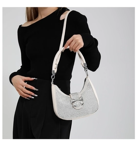 Detail of silver crescent bag with rhinestones, metal bow, and shoulder strap on model