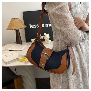 Detail of color-block denim and brown leather saddle bag with buckle in retro setting