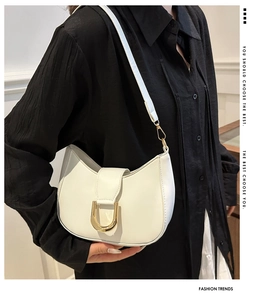Detail of a minimalist off-white crescent saddle bag with a golden D-shaped clasp