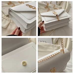 Detail view of white leather crossbody bag with gold chain, tassel, and magnetic snap