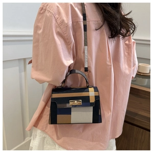 Detail of color-block checkered crossbody bag with gold metal clasp and top handle
