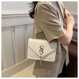 Detail of white envelope chain bag with gold S-logo and metallic tassel on a blazer