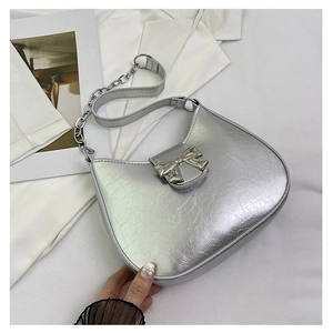 Detail of silver crescent bag with metallic cracked leather and bow buckle