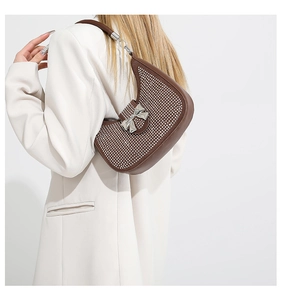 Detail of a brown hobo bag with sparkling rhinestones and a silver metal bow buckle