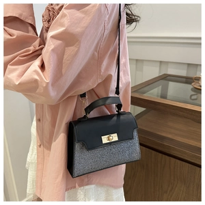 Detail view of the black sequin and leather handbag with a gold twist-lock closure
