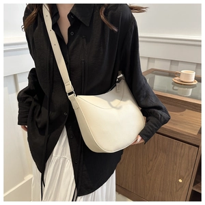 Side view of cream pebble leather crescent bag worn by a model in casual setting