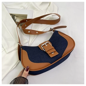 Detail of retro denim saddle bag with contrast leather trim and silver metal buckle