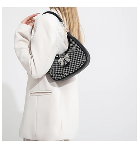 Detail of a black crescent bag with rhinestones and a silver bow on a female model