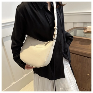 Detail of a cream crescent hobo bag showing pebbled leather texture and adjustable strap