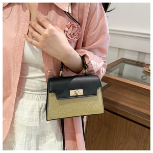 Detail of glitter contrast handbag with gold metallic twist lock and black top handle