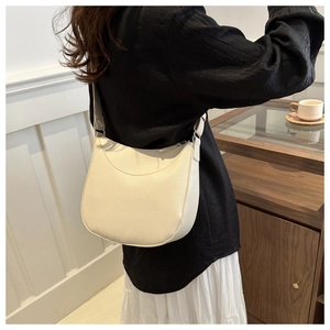 Detail of cream crescent shoulder bag with pebbled leather texture and silver buckle