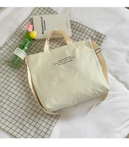 Detail of beige canvas tote bag with adjustable shoulder strap and fashion typography