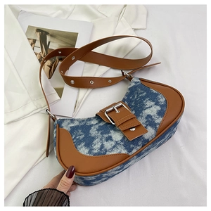 Detail of vintage denim and brown leather contrast stitching on the saddle bag