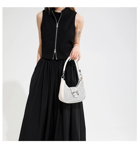 Close-up of sparkling white rhinestone hobo bag with silver metal bow on black outfit