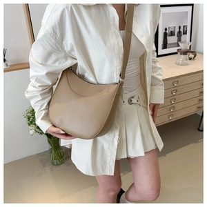 Detail shot of beige half-moon hobo bag with lychee grain texture and silver hardware