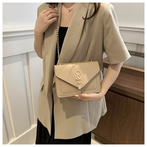 Detail of beige chain bag with gold SS clasp and fringe tassel on a blazer-clad model