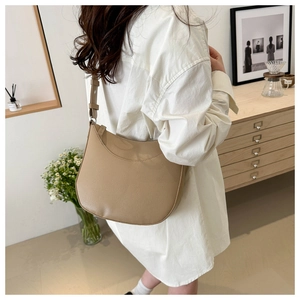 Close-up of a minimalist light brown crescent hobo bag with textured pebble leather