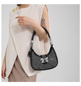 Close-up of sparkling black rhinestone crescent bag with silver metallic bow detail