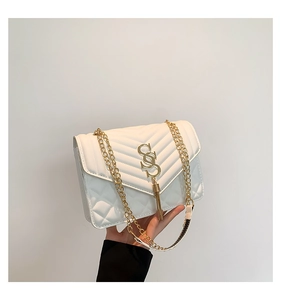 Detail der weißen Stepptasche mit goldenem SS-Logo, Quasten und Metallkettenriemen