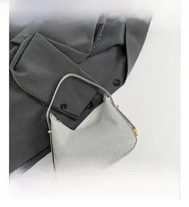 Detailed view of grey woven shoulder bag with golden metal buckle and sleek design