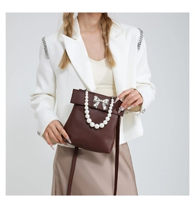 Détail du sac bandoulière en cuir marron foncé avec anse perle et boucle noeud argent