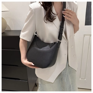 Detail of black pebbled leather crescent crossbody bag with adjustable wide shoulder strap