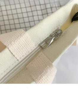 Detailed view of silver metal zipper closure and textured canvas on the tote bag