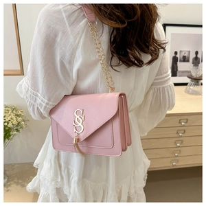 Close-up of pink leather handbag featuring a gold S-shaped logo and metallic tassels