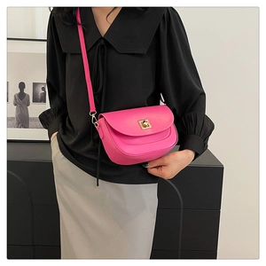 Détail du sac selle rose fuchsia avec boucle dorée et bandoulière en cuir ajustable