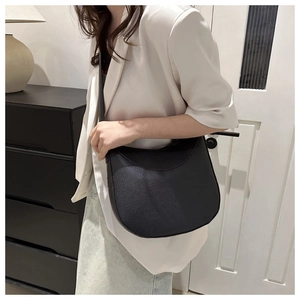 Minimalist black lychee pattern leather crescent shoulder bag for women worn by model