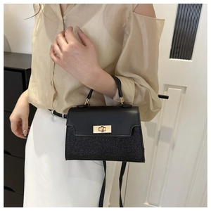 Close-up of contrast stitching handbag with gold metal twist lock and glitter texture