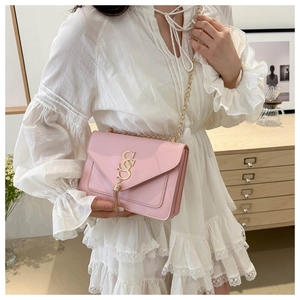 Detail showing the light pink square bag with gold tassel and dual S logo on the flap