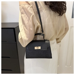 Detail of black sequined crossbody bag showing the glitter texture and gold metal twist lock