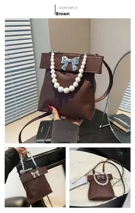 Detail of a brown leather bag with large pearl handle and silver metal bow decoration