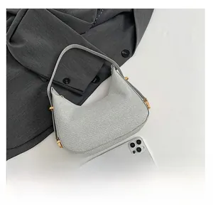 Close-up of gray woven fabric hobo bag with gold buckle next to a smartphone