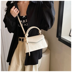 Détail du sac à main blanc crème mat avec poignée à nœud et texture plissée élégante