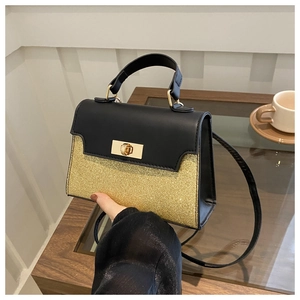 Detail of elegant black and gold contrast handbag with glitter finish and metal turn-lock