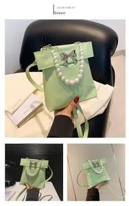 Close-up of green PU leather handbag featuring silver bow buckle and pearl handle chain