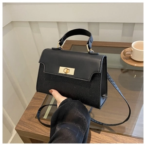 Close-up of black handbag with contrast matte leather, glitter finish and gold lock