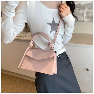 Détail d'un sac à main rose avec poignée nouée, fini texturé et détails dorés chics
