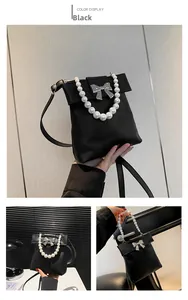 Detail of black matte bag with large pearl handle and silver bow accent for women