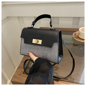 Detail of silver glitter and black leather contrast handbag with gold metal clasp and strap