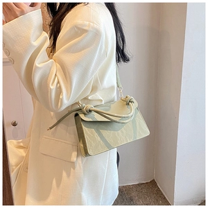 Détail du sac vert clair montrant la poignée nouée et la texture du cuir marbré
