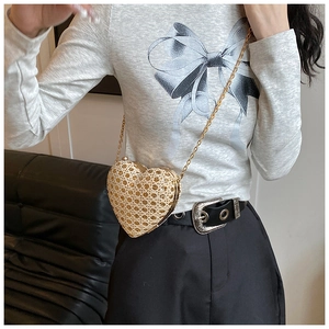 Close-up of heart-shaped gold mini bag with sequined mesh and thin metal chain strap