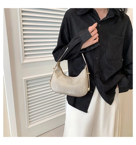 Detail of champagne gold sequined hobo bag with adjustable strap worn by a model