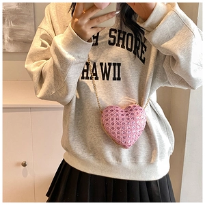 Fashionable pink heart-shaped crossbody bag with rhinestones and gold chain worn by model