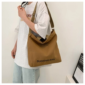 Brown canvas messenger bag shown cross-body with adjustable strap and large capacity
