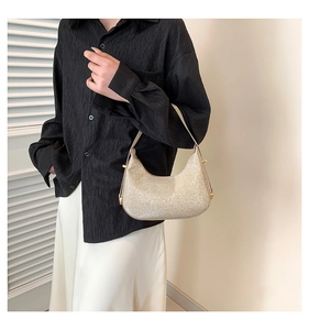 Close-up of golden glitter hobo bag featuring metallic finish and cylindrical hardware
