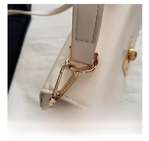 Detail shot of golden hardware accents and smooth cream leather on a stylish handbag