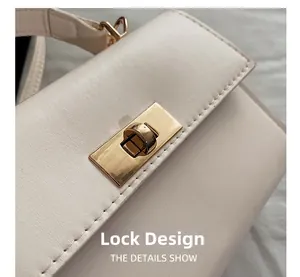Detail of elegant gold metal twist lock closure on a cream minimalist crossbody bag
